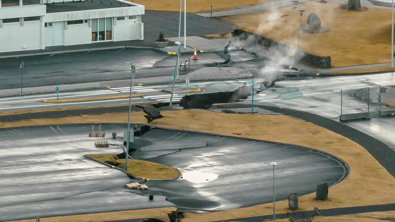 Aus Rissen im Boden in der isländsichen Stadt Grindavik steigt Rauch auf (Luftaufnahme mit Drohne).